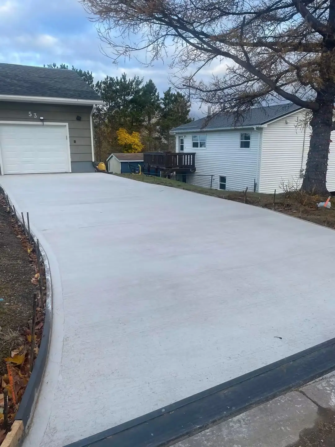 Long finished concrete driveway with a curved edge running to a garage