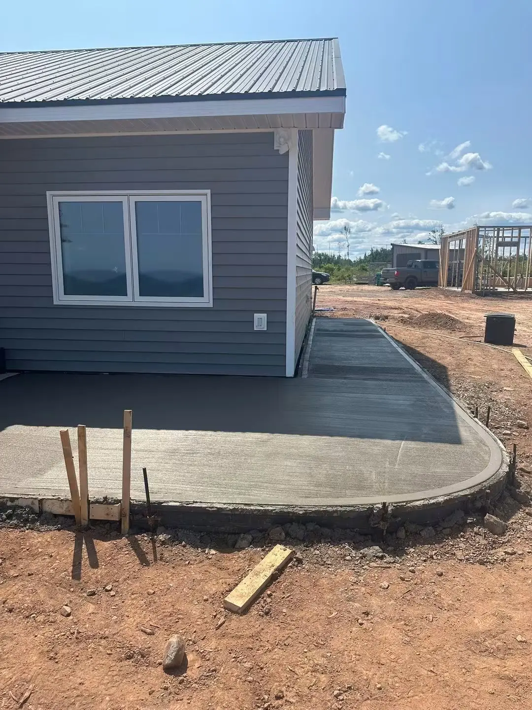 Concrete patio with a rounded corner beside a grey house