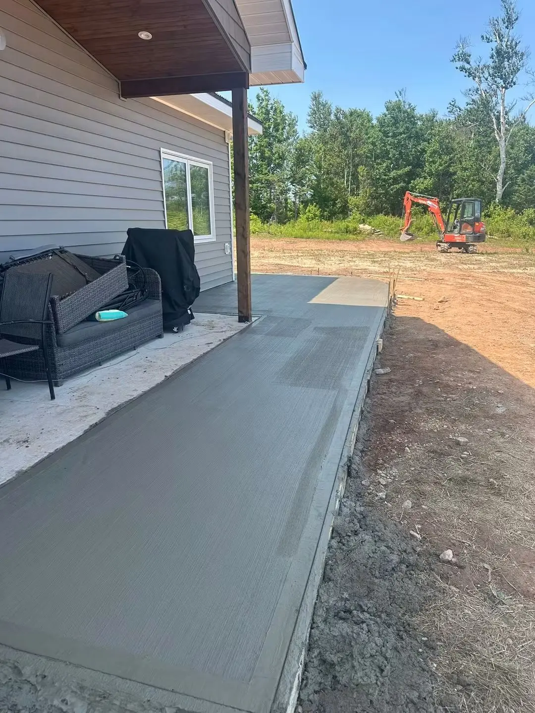 Fresh concrete patio poured under a covered porch