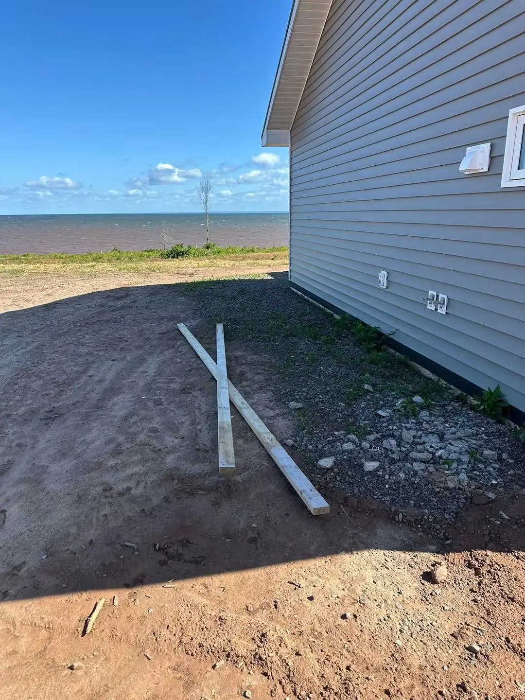 Bare ground beside a shoreline home before the side patio was poured