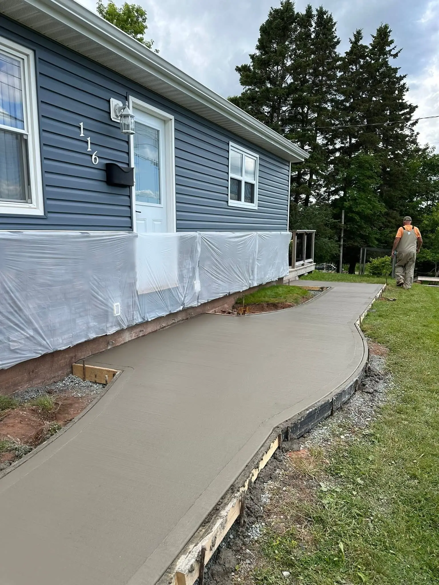 Curved concrete walkway along a newly built blue house